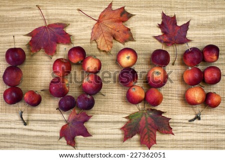 Word love with small red-ripe apples and maple leaves on wooden board. Sweet holiday background. Image of natural materials. Eco style.