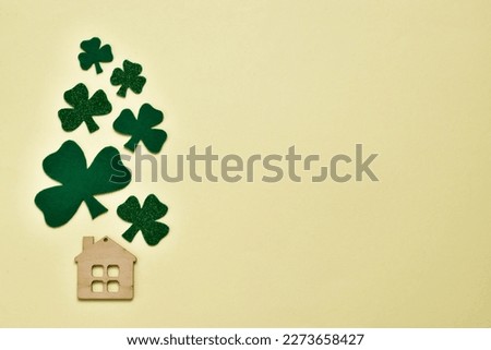 Lucky home symbol with leaves clover on light yellow background. Copy space. St.Patrick's day holiday symbol. Greeting card