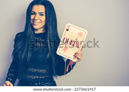 .
Portrait of Beautiful smiling  Happy woman   Celebrating birthday holding a  red party photo booth  props accessory with phrase  Queen .isolated ,Celebration, fun and holiday concept.