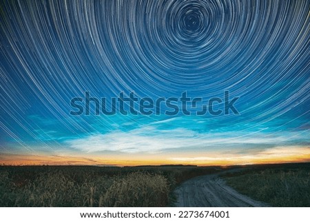 Morning Sunrise In Countryside. Unusual Amazing Effect Of Cloud And Stars Trails Above Countryside Rural Field Landscape With Young Green Wheat Sprouts In Springtime. Soft Colors. Royalty-Free Stock Photo #2273674001