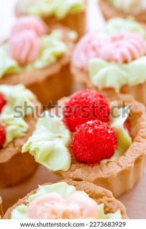 Group of mini tarts decorated with raspberries and cream.