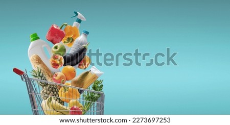 Fresh groceries and goods falling in a supermarket trolley, grocery shopping concept Royalty-Free Stock Photo #2273697253