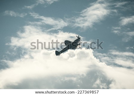 Old fighter plane on bright cloudy sky