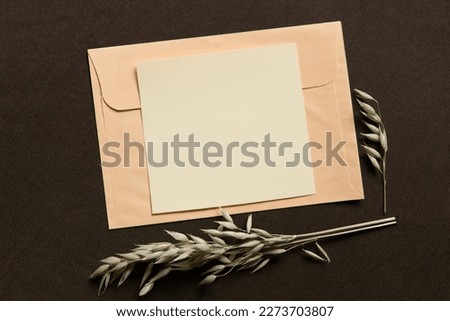 Blank greeting card, invitation and envelope mockup. Minimal floral frame made of dry flowers and branches. Flat lay, top view. Happy mother's day, women's day or birthday, wedding composition.
