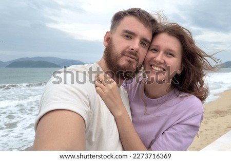 Happy couple in love is enjoy summer vacation on sea, beach take selfie photo, picture of themself on phone, smartphone, hug each other 