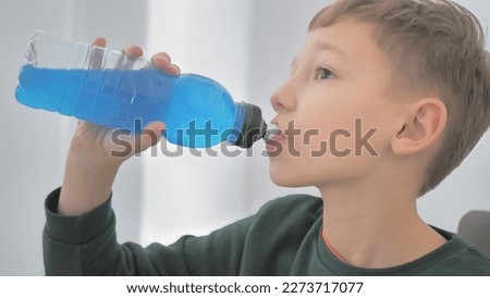 Taking a break. Side view of sporty teenager drinking blue energy drink. Youth and sports Royalty-Free Stock Photo #2273717077