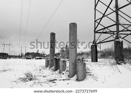 High-voltage power lines in a snowy field. Black and white photo.