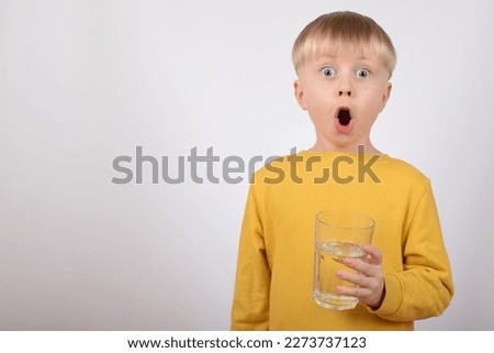 portrait of a child, a boy, holding a glass of water in his hands