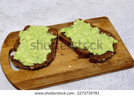 Two slices of avocado toast on a wooden cutting board isolated, close-up