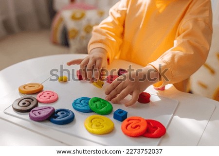A little girl play with plasticine and colorful numbers.  Learning to count through play. Early education. Fine motor skills, creativity and  hobby. Royalty-Free Stock Photo #2273752037