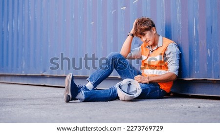 male engineering of containers in shipping logistic company sitting unhappy stressed after being laid off. Employees working in a container shipping company sit stressed and tired from work. Royalty-Free Stock Photo #2273769729