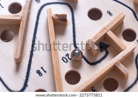 Wooden labyrinth toy marble maze game. Ball bearing navigating a vintage traditional wooden maze, close up, macro shot
