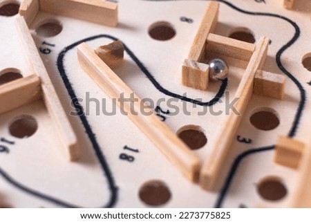 Wooden labyrinth toy marble maze game. Ball bearing navigating a vintage traditional wooden maze, close-up Royalty-Free Stock Photo #2273775825