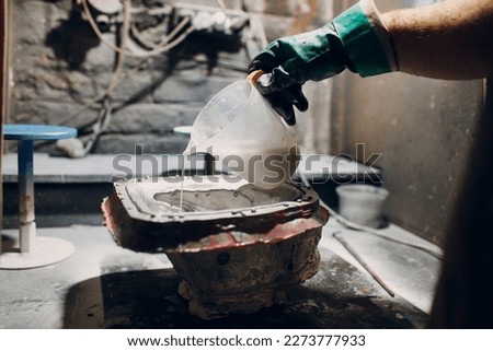 Artisan craftsman pour liquid plastic mask based on plaster cast. Gypsum mold and plastic mask sculpting. Royalty-Free Stock Photo #2273777933