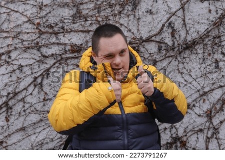 A young man with Down's syndrome gives the thumbs up sign outside in Oxford, England Royalty-Free Stock Photo #2273791267