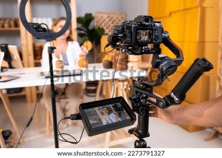 Behind the scenes of A young pretty woman entrepreneur live streaming to sale craft products to customers via filming professional camera