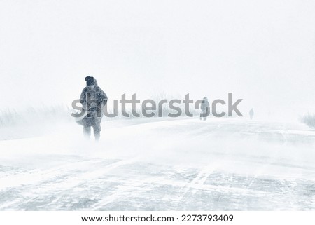 the snowstorm is cold a person has fallen into extreme living conditions is walking along the road through a blizzard in the city, the winter is cold. Royalty-Free Stock Photo #2273793409