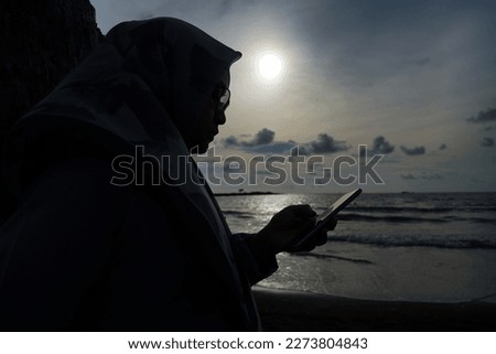 silhouette of a woman holding a cell phone