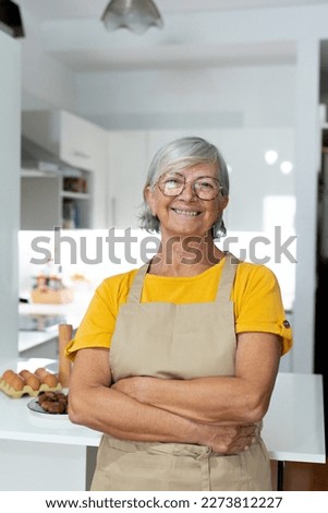 Happy senior 60s lady looking at camera, smiling. Cheerful homeowner woman, food blogger preparing ingredients for dinner. Head shot portrait preparing dinner or lunch.