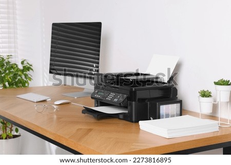 Modern printer with paper near computer on wooden table in office Royalty-Free Stock Photo #2273816895