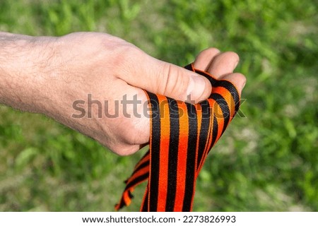 St. George's ribbon of a man's hand on a background of spring greenery