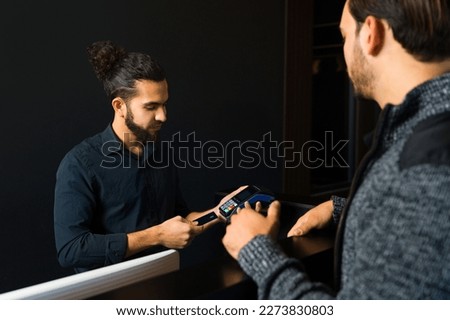 Customer paying with a credit card to a business owner of a barber shop after getting a haircut