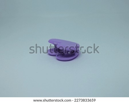 Cute simple purple colored small paper clip isolated on plain white background. Office or school study equipment themed image.