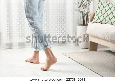 Barefoot man walking on white parquet at home, closeup. Heated floor Royalty-Free Stock Photo #2273840091