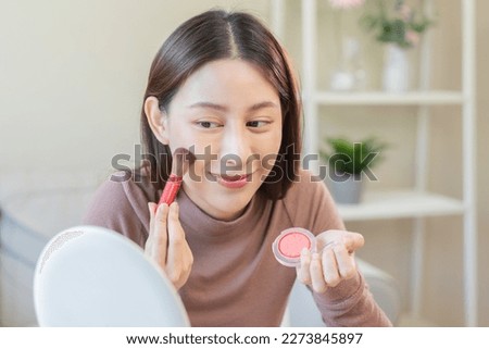Happy beauty blogger concept, cute asian young woman, girl smile, make up face by applying brush blush powder on her cheek, looking at the mirror. People look with natural fashion style. Royalty-Free Stock Photo #2273845897