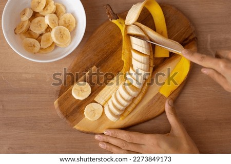 woman cutting banana slices. sliced banana. banana slices. preparing fruit salad. healthy foods. Royalty-Free Stock Photo #2273849173