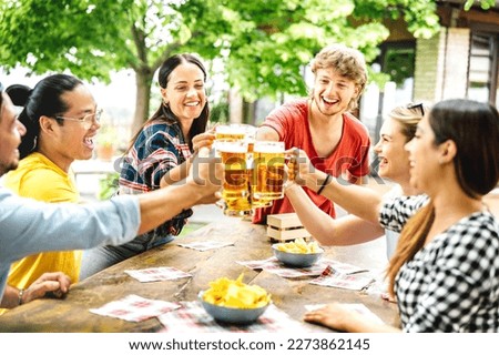 Young happy friends drinking and toasting beer at brewery bar farm house patio - Beverage life style concept with genuine guys and girls having fun together at picnic out side - Bright vivid filter Royalty-Free Stock Photo #2273862145