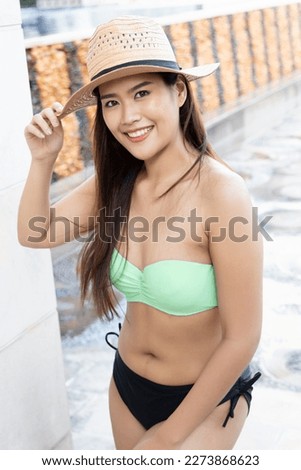 Happy smiling relaxed summer woman wearing bikini swimsuit with hat at swimming pool