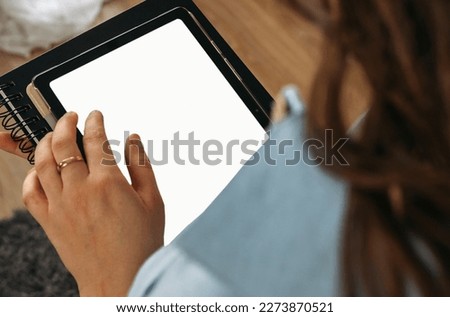 A woman holds a tablet in her hands, on the screen of which there is free space. Mockup. View from above.
