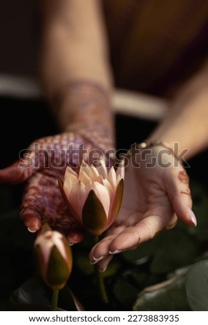 Mehndi adorns the women's hands with a beautiful flower design.Vesak day, Buddhist lent day, Buddha's birthday worshiping concept with woman's hands holding water lilly or lotus flower  Royalty-Free Stock Photo #2273883935
