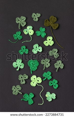 St Patrick's Day side border made of knitted green shamrocks on a black background. Holiday sign and knitted clover leaf. Copy space, flat lay
