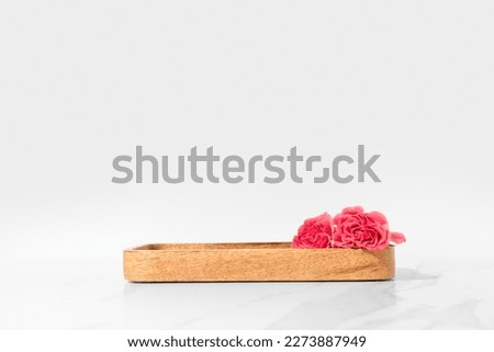 Cosmetics product presentation scene made with wooden tray pedestal and pink roses on white background. Studio photography.