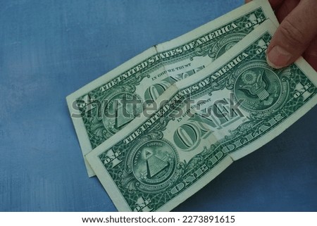            a hand holding two one dollar bills                     Royalty-Free Stock Photo #2273891615