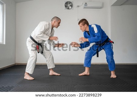 Brazilian jiu jitsu bjj training or sparing two athletes fighters dill martial arts technique at gym on the tatami mats wear kimono gi black belt instructor demonstrate technique stand up Royalty-Free Stock Photo #2273898239