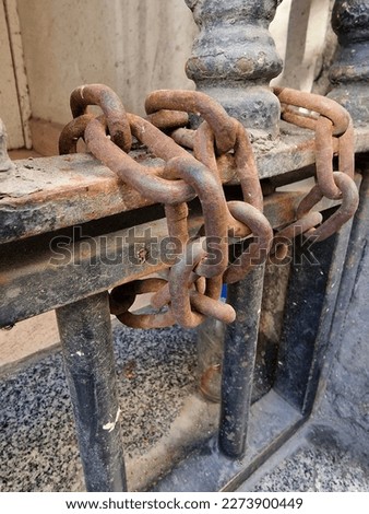 Old rusty chain entwining the metal gate of one of the tenement houses in the Old Town of Madrid, Spain.