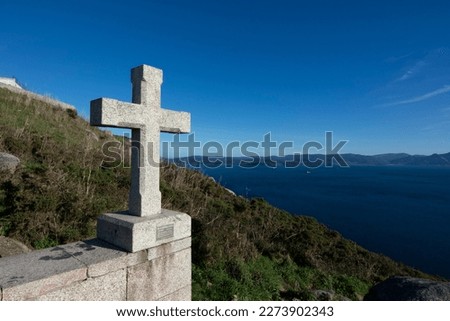 Stone cross at the end of the Route of Santiago with sea background