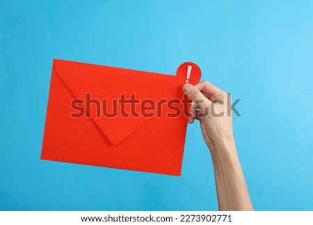 Hand holding red envelope with important notification on blue background. Social media, message, sms, subscribe notice alert and reminder.