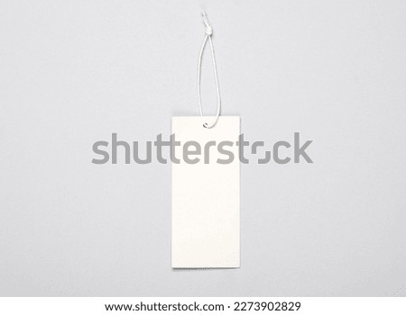 White blank clothing price tag or label mockup with string on gray background. Sale, shopping concept. Top view