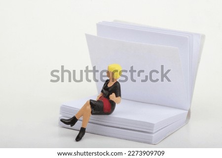 miniature figurine of a woman sitting on a big book