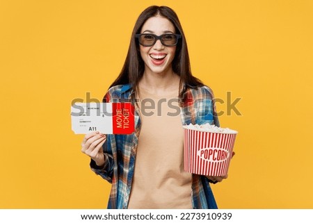 Young laughing excited cool satisfied fun cheerful joyful happy woman wear 3d glasses watch movie film holding ticket bucket of popcorn in cinema isolated on plain yellow background studio portrait
