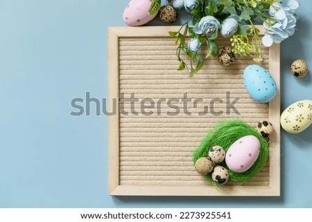 Springtime welcome concept. Letter board, Easter eggs and spring flowers on a pastel blue background, minimalism style composition. View from above. Copy space.
