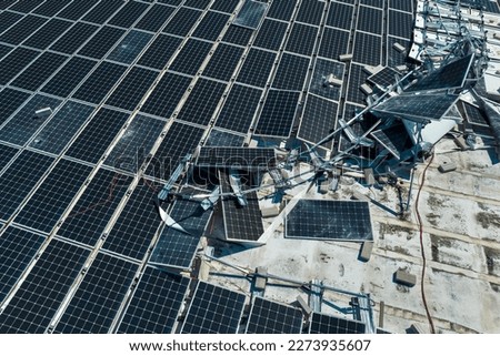 Aerial view of damaged by hurricane wind photovoltaic solar panels mounted on industrial building roof for producing green ecological electricity. Consequences of natural disaster Royalty-Free Stock Photo #2273935607