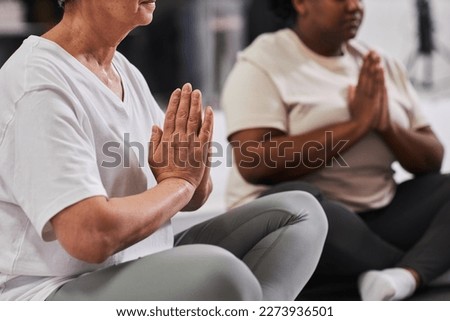 Close-up of women sitting in lotus position and meditating during yoga class
