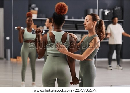 Rear view of African American woman training with dumbbells together with instructor in gym Royalty-Free Stock Photo #2273936579