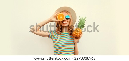 Summer portrait of happy smiling young woman with pineapple and slice of orange, fresh tropical juicy fruits, wearing straw hat, sunglasses on white background Royalty-Free Stock Photo #2273938969