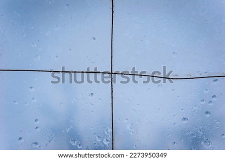 Home-made construction, a canopy, a greenhouse made of transparent cloth against the sky. Raindrops on the surface. Texture, abstraction, close-up photography.